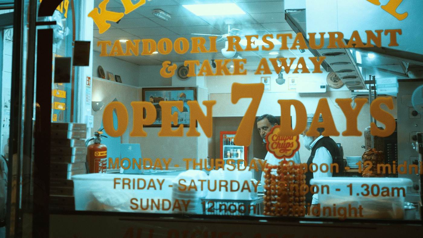 A tandoori restaurant lit up behind its window after dark.